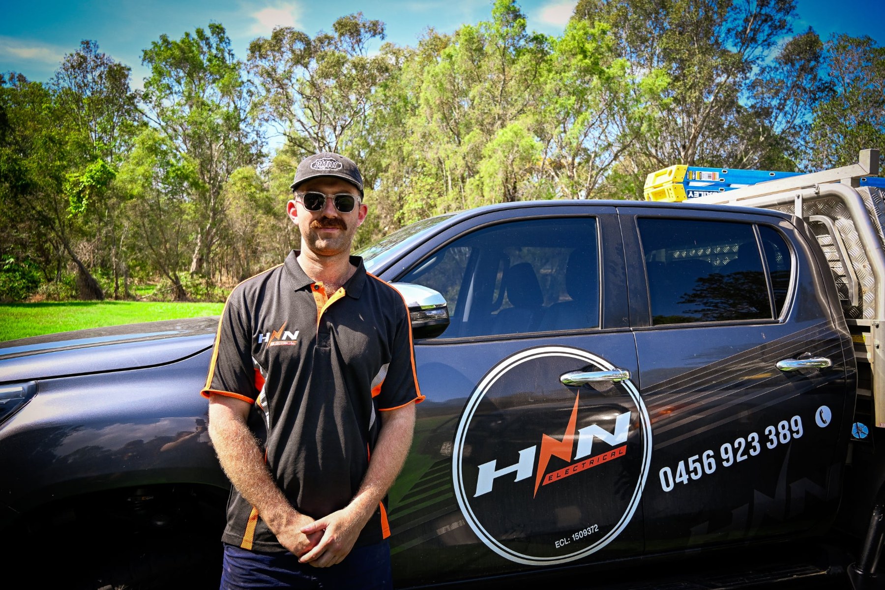 HNN Electrical employee beside a branded company vehicle